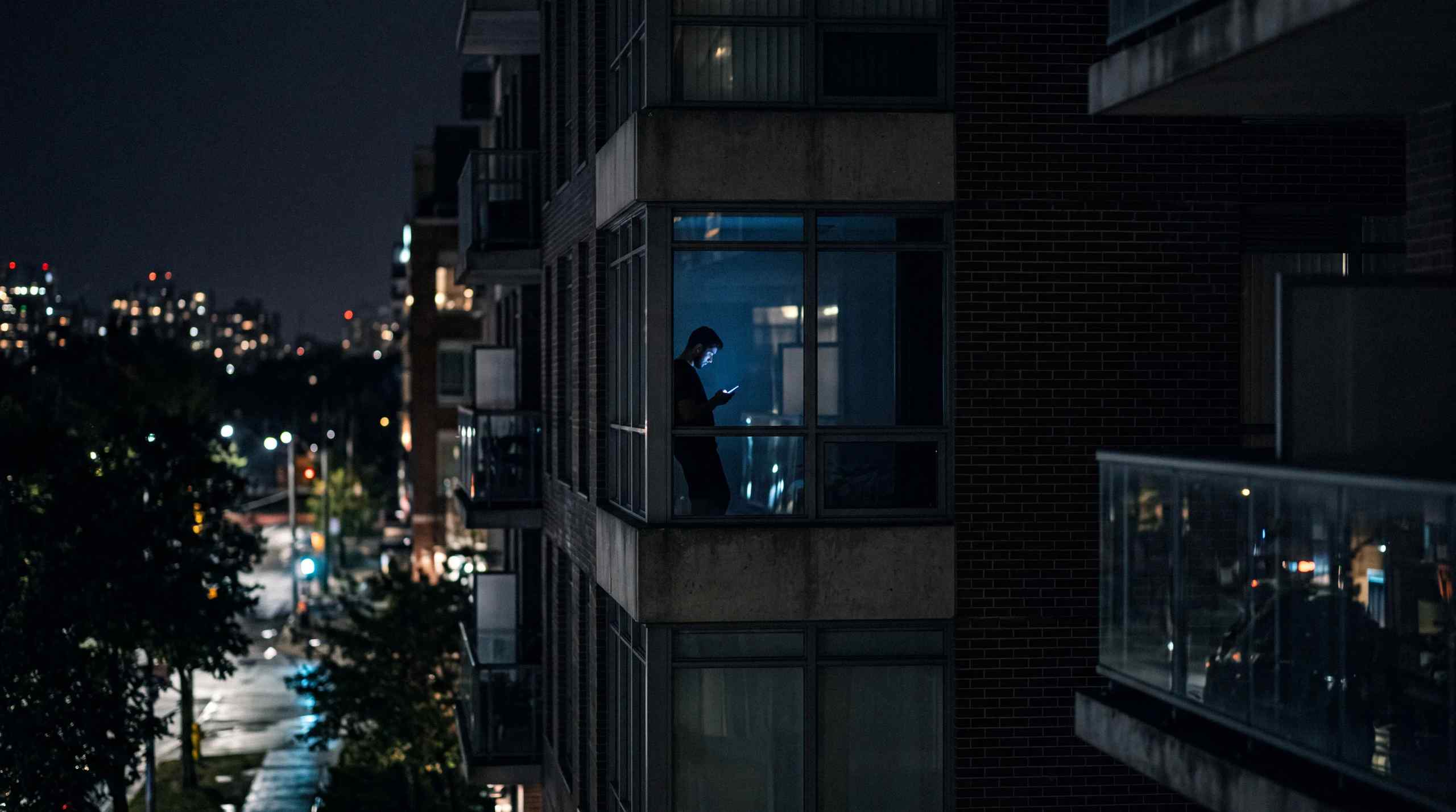 A man in an apartment at night on his phone.